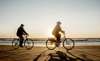 Two people cycling on the beach at sunset near Vedersø Strand Camping.
