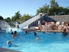 View of the swimming pool with water slide and sunbathing guests at Blushøj Camping.