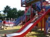 Children having fun on the colourful campsite playground with a slide.