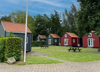 Cabins at Slagelse Camping – charming red and dark cottages surrounded by green nature in West Zealand, Denmark.