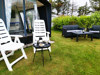 Cozy seating area with garden furniture and a table in front of a caravan at Nissum Fjord Camping.