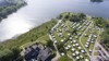 Luftaufnahme vom Maribo Sø Camping mit Zelten, Wohnwagen und dem See im Hintergrund.
