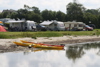 Kayaks on the shoreline at Nibe Camping with caravans in the background.